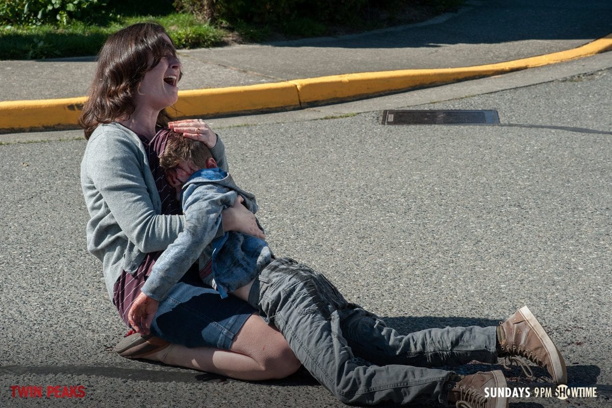 A mother screams as she holds the dead body of her son who has been hit by a truck