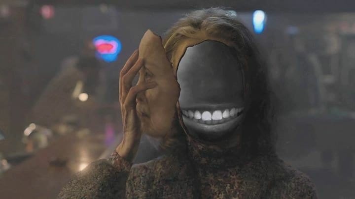 Sarah Palmer removes her face to reveal a black space with a grin