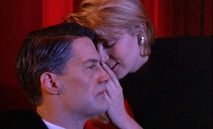 Laura Palmer whispers in the ear of an aged Dale Cooper in the red room