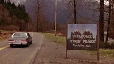 car driving by the welcome to twin peaks sign
