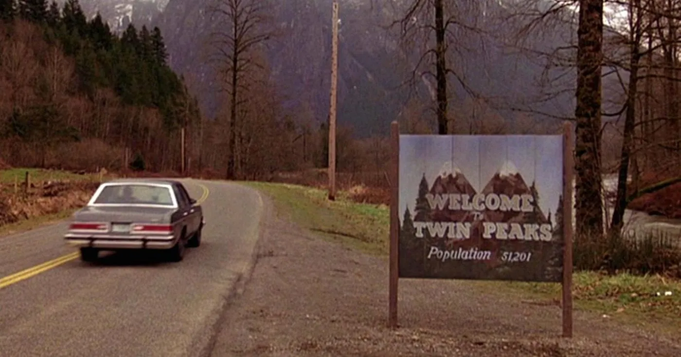car driving by the welcome to twin peaks sign