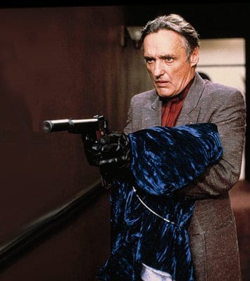 Frank Booth holds a gown of blue velvet as he holds up a gun