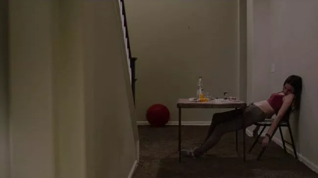 drugged out mom collapsed at a table, a red balloon is on the floor