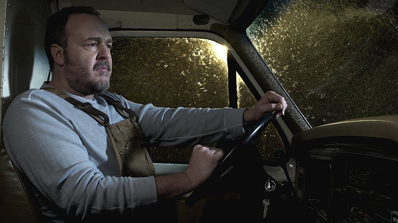 Brent Sexton as Stan Larsen sits in the front of his van in the dark and rain in The Killing