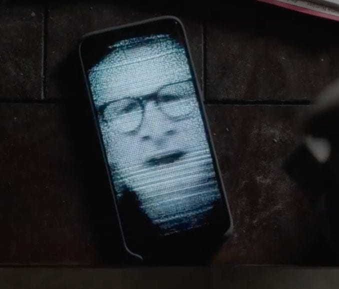An image of a mans distorted face on a cell phone