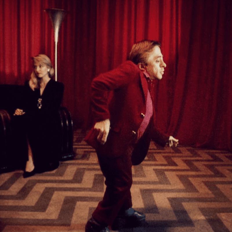 The little man from another place dances in the red room with Laura seated in the background