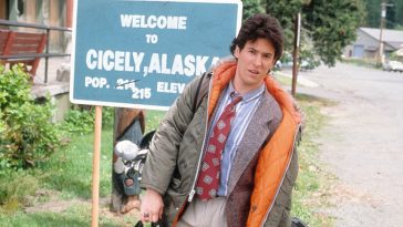 Joel stands at the Cicely town welcome sign