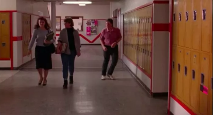 Boy dances in the hallway as two girls walk down it