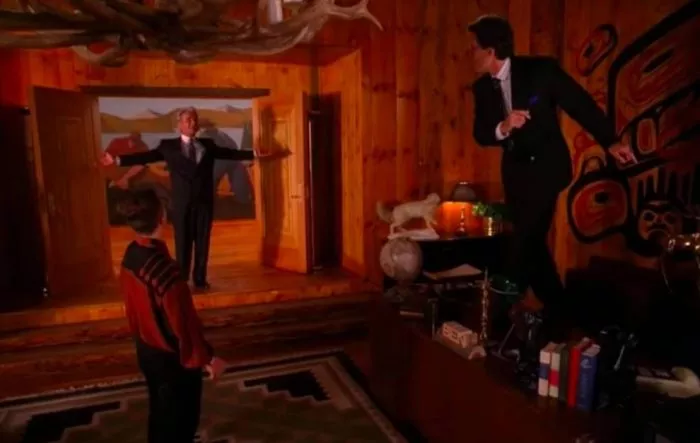 Leland stands in Bens doorway arms outstretched as Ben and Jerry dance