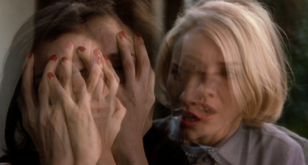 Rita (left) covers her face with her hands while Betty (right) tries to comfort her. Image altered by Lynch with a superimposition effect.