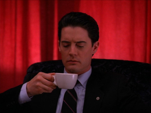 Cooper holding a cup of coffee in the red room