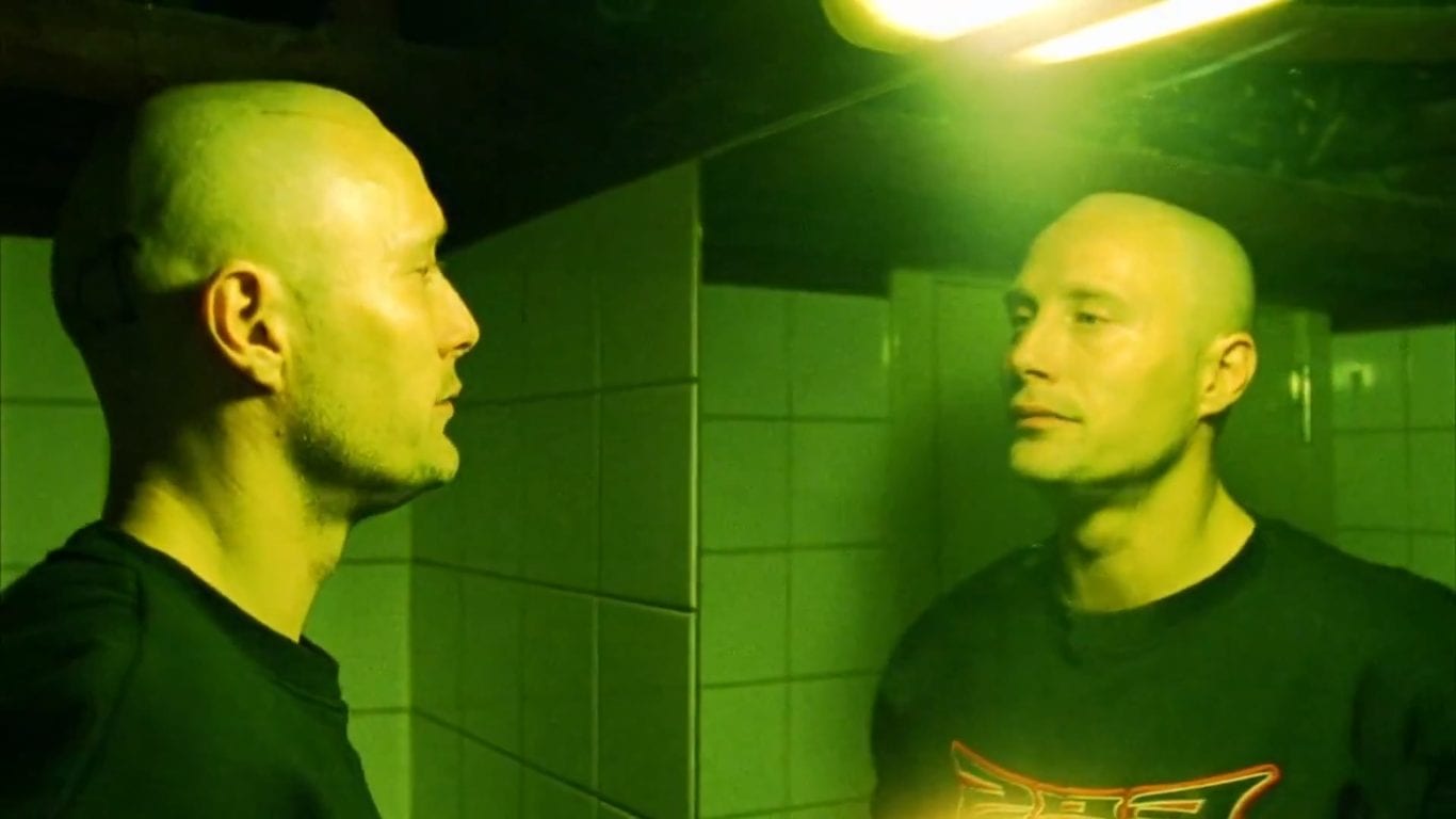 Mads Mikkelsen in Pusher looking at himself in a mirror lit in green