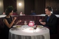 Frank and Amy prepare to look at the expiry dates on their phones as they prepare to eat at a restaurant on their first date