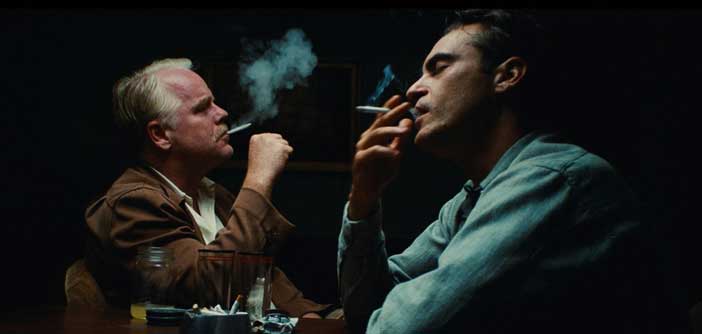 Phillip Seymour Hoffman and Joaquin Phoenix smoke in a black room