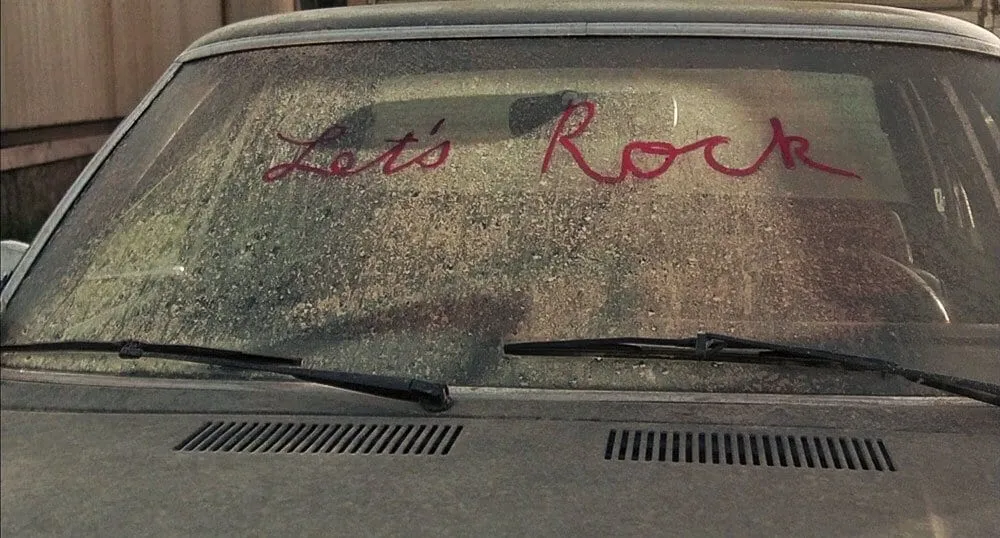Let's Rock written in lipstick on a dirty car windscreen