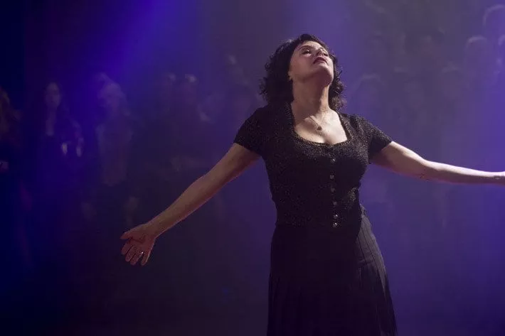 Audrey, arms outstretched while dancing in front of a purple lit room