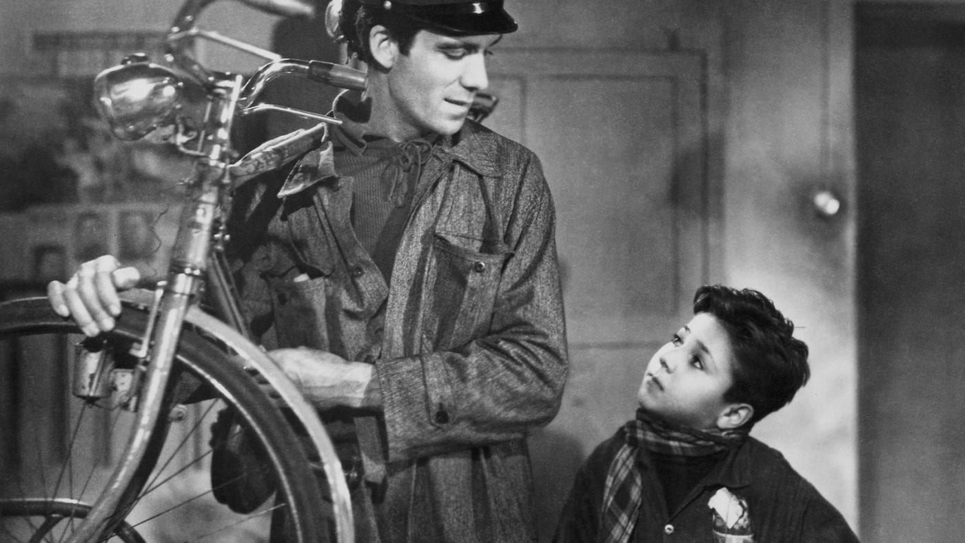 a boy looks up at a man admirably as he steals a bike