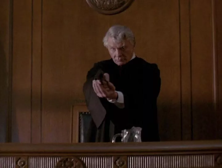 Steve Forrest as Judge Murdoch holding a gun in his bench
