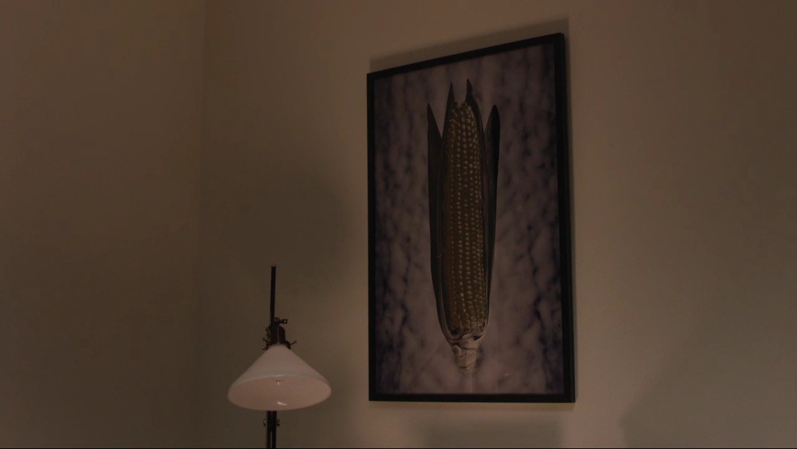 the painting of an ear of corn in a cloudy background hangs in Gordon Coles office