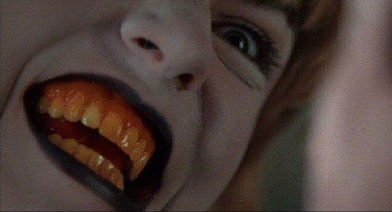 Laura Palmer with a white face, black lips and yellow teeth 