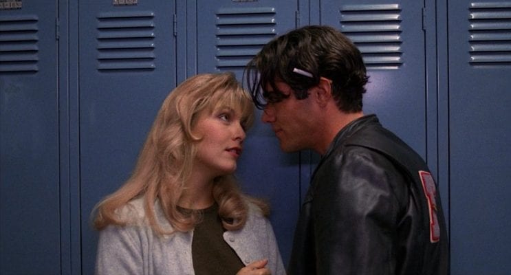Laura and Bobby talk in front of a row of lockers