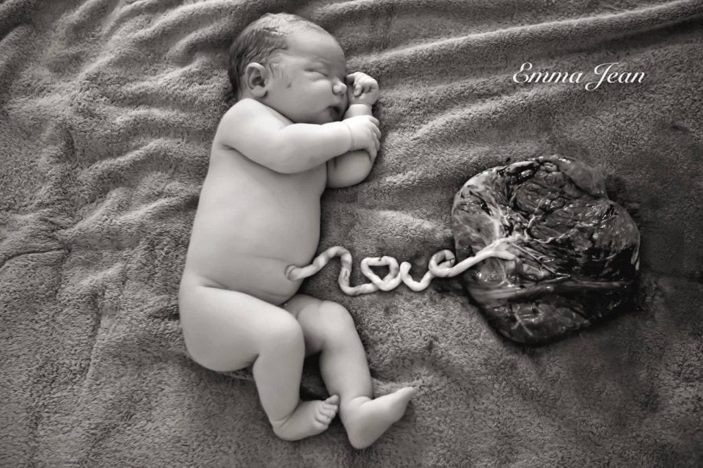 a newborn baby lying next to its placenta, the word love spelled out with the umbilical chord