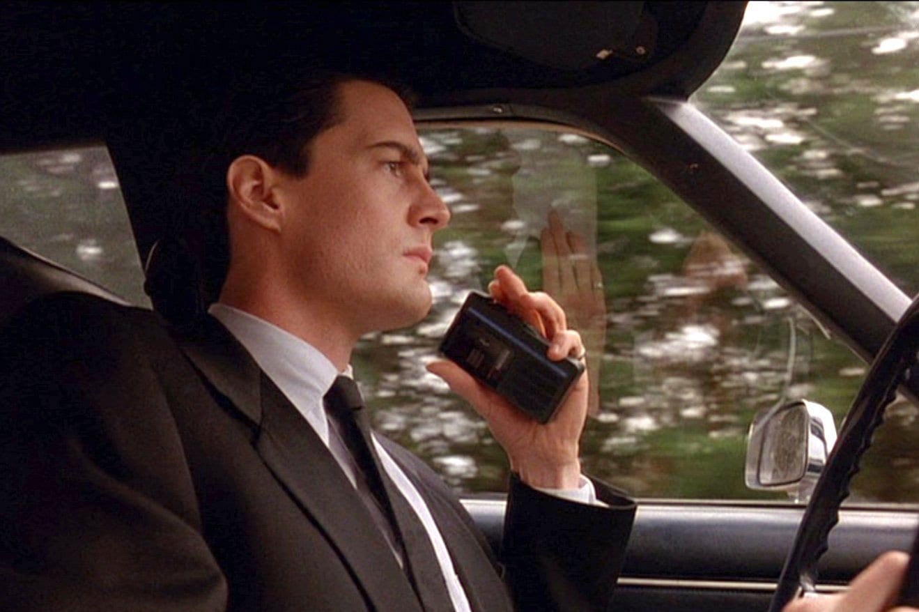 Agent Cooper speaking into his recorder, entering Twin Peaks