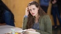 Hannah Baker (Katherine Langford) sits at a table with a book in 13 Reasons Why