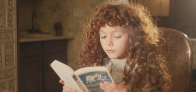Nadia as a girl, seen in a flashback reading Emily of New Moon.