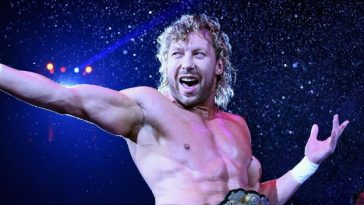 The wrestler Kenny Omega stretches his hand out in a gun shape, in his signature 'goodbye and goodnight' pose
