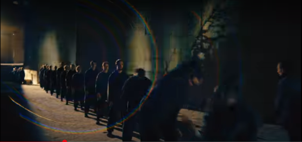 A line of men in black clothing a darkened subway