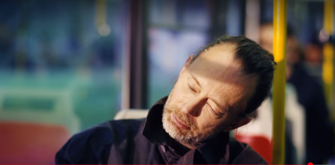 Thom Yorke rests his head and closes his eyes while travelling on the tube train