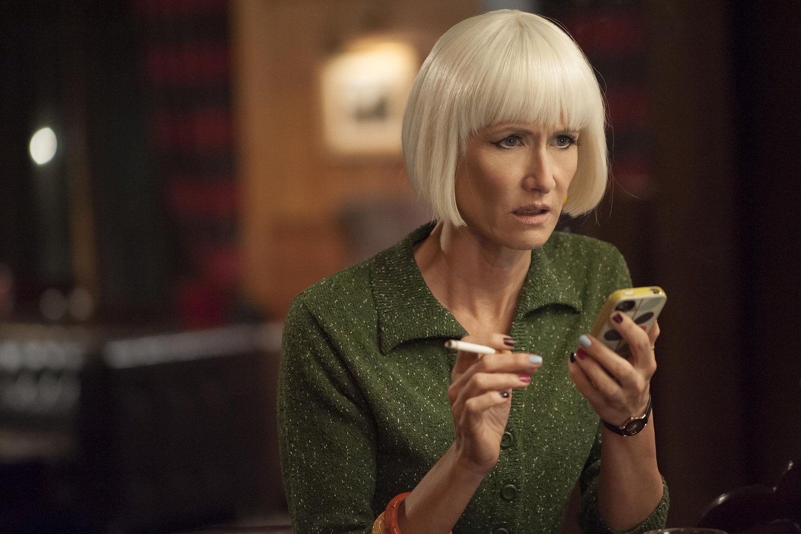 Blonde Diane with a shocked expression after reading a text message.