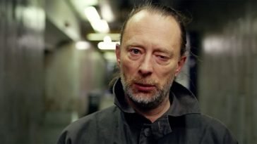 A close-up shot of Thom Yorke's face as he walks down a tunnel
