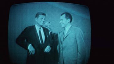 JFK and Nixon stand next to each other on TV prior to their debate