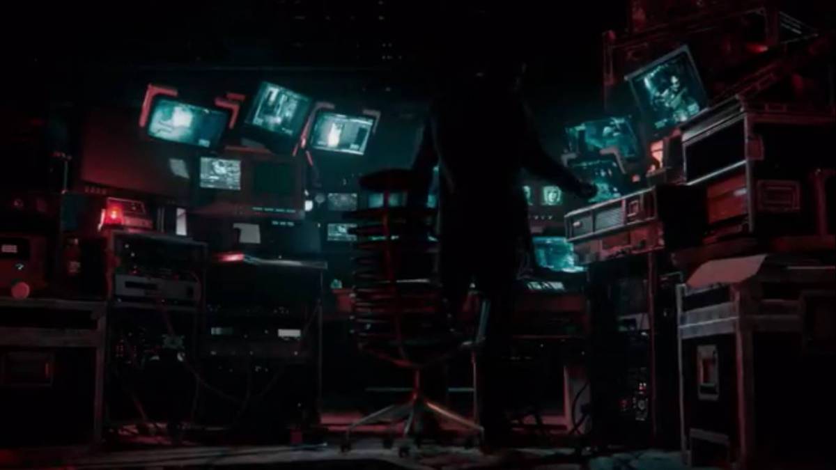 A dark figure in a room full of computers and monitoring equipment