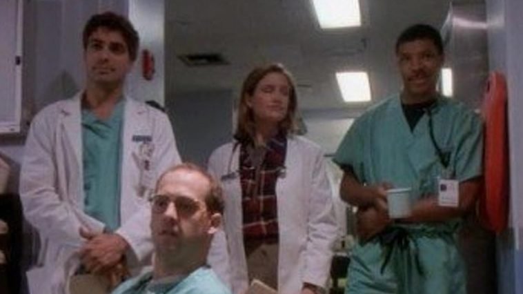 Doctors Ross, Lewis and Benton look on in the ER hallway at the new interns, and Doctor Greene looks with them while seated.