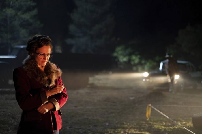 Roma waits on the dark plot, smoking, as the car approaches
