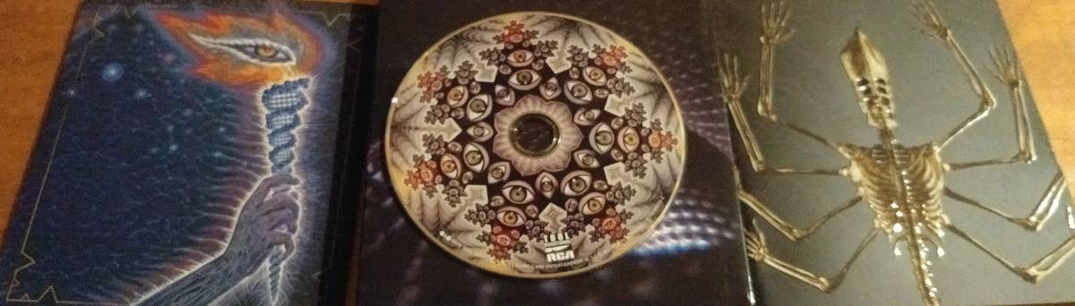 The CD of Tool's Fear Inoculum on its casing, framed by an image of the included booklet, which features a torch with an eye for the flame, and an image of a skeleton with many army and what appears to be a Pope's hat
