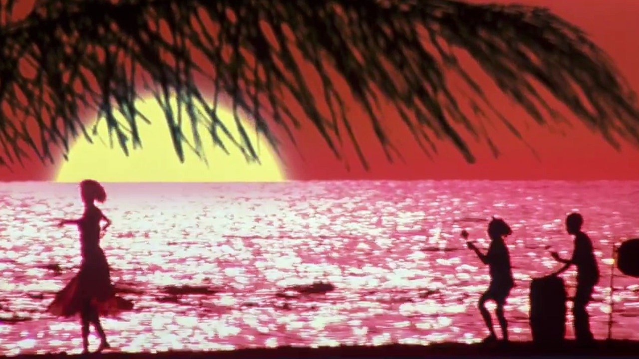 Gail dances in silhouette on a beach against a red sky with a huge yellow sun, whilst a band plays in the background