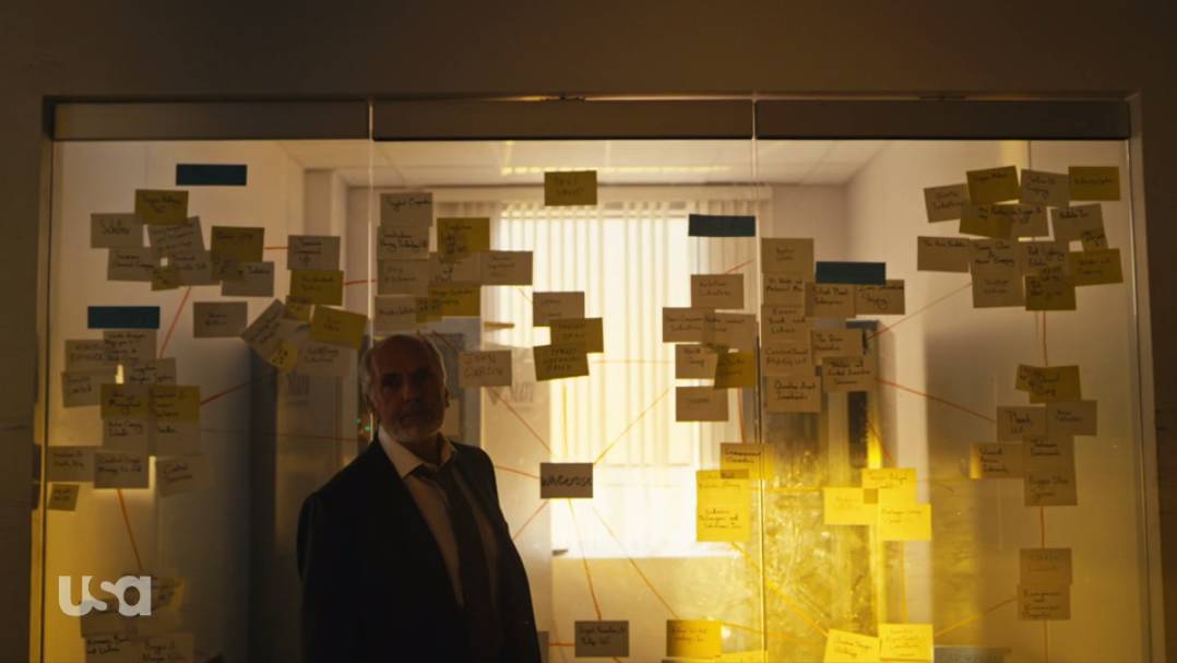 Price stands in front of Elliot's board of post-it notes