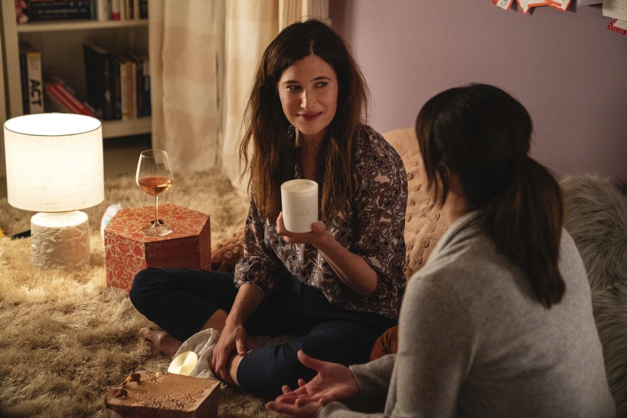 Eve sits crosslegged on the floor with Jane, holding the candle Jane bought her