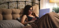 Eve looks at her laptop in bed