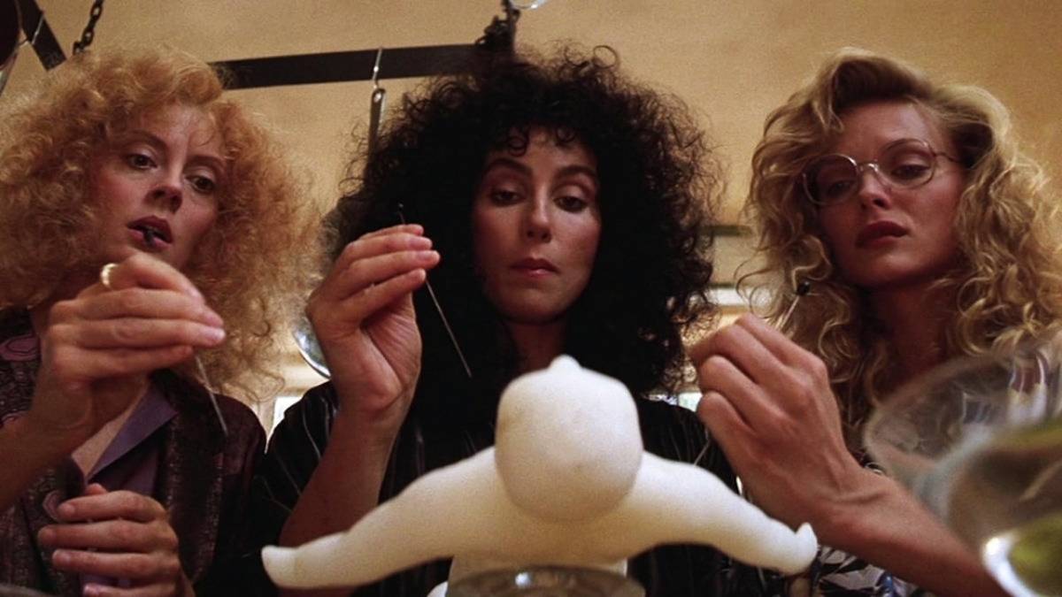 The three witches played by Susan Sarandon, Cher and Michelle Pfeifer gather around a wax voodoo doll