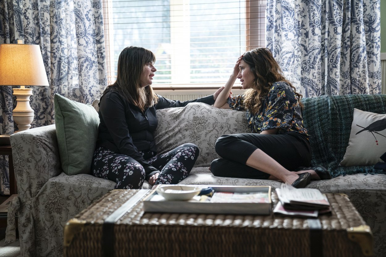 Eve and Jane sit opposite each other on the couch as Eve consoles Jane