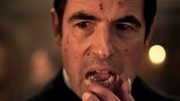 Claes Bang as Dracula wipes his lip with a finger