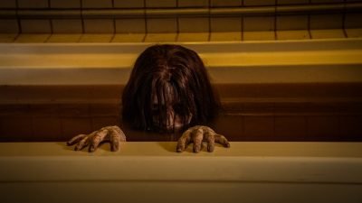 A ghost of a young girl peering her head above the water in a bath