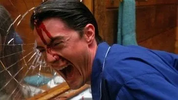 Cooper laughs maniacally with blood on his face after breaking a mirror with his head