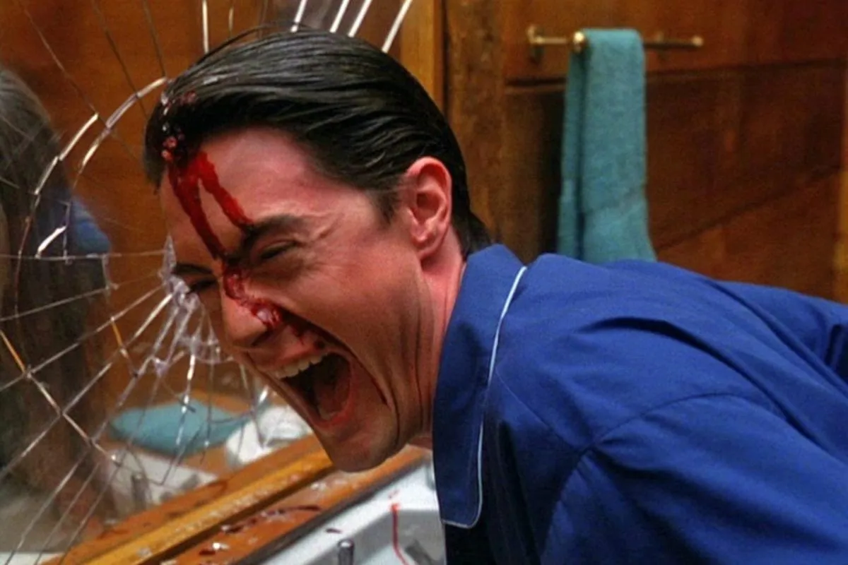 Cooper laughs maniacally with blood on his face after breaking a mirror with his head