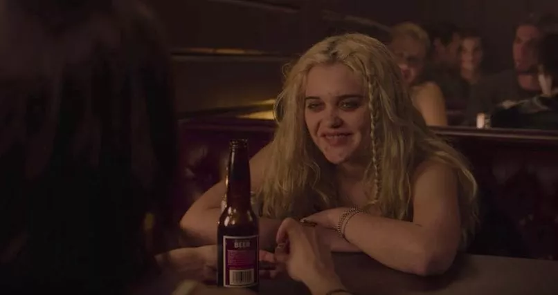 Chloe at the Roadhouse, leaning forward in a booth while smiling about her unsavory lifestyle.